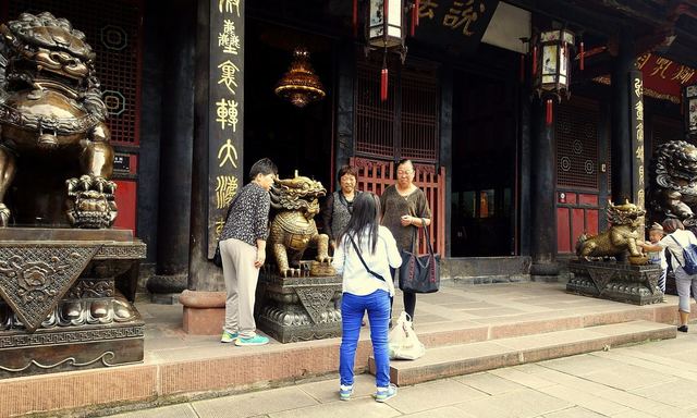 A bronze guardian lion on its pedestal at the entrance to Wenshu Monastery