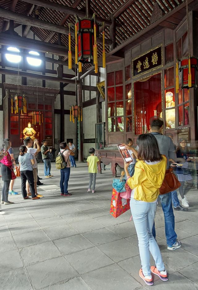 A red lantern and gilded statue in a timber hall at Wuhou Shrine